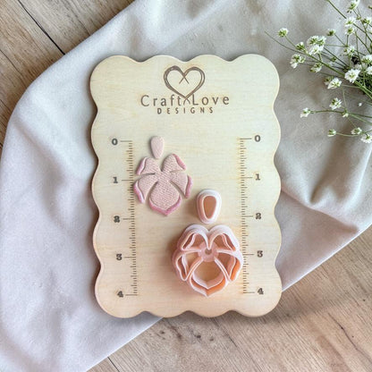 Polymer clay cutter set with tropical flower shape and matching top piece displayed on a wooden measuring board with ruler markings.