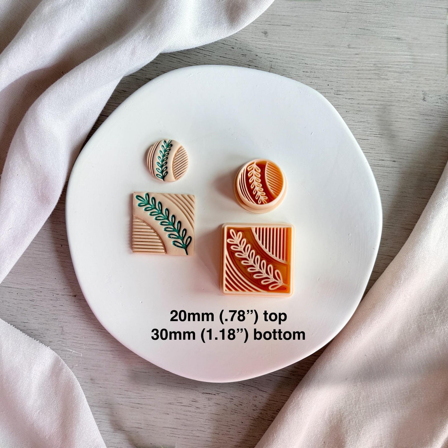 Polymer clay cutter set showing square and circle shapes with leaf pattern next to finished clay pieces on a white plate.
