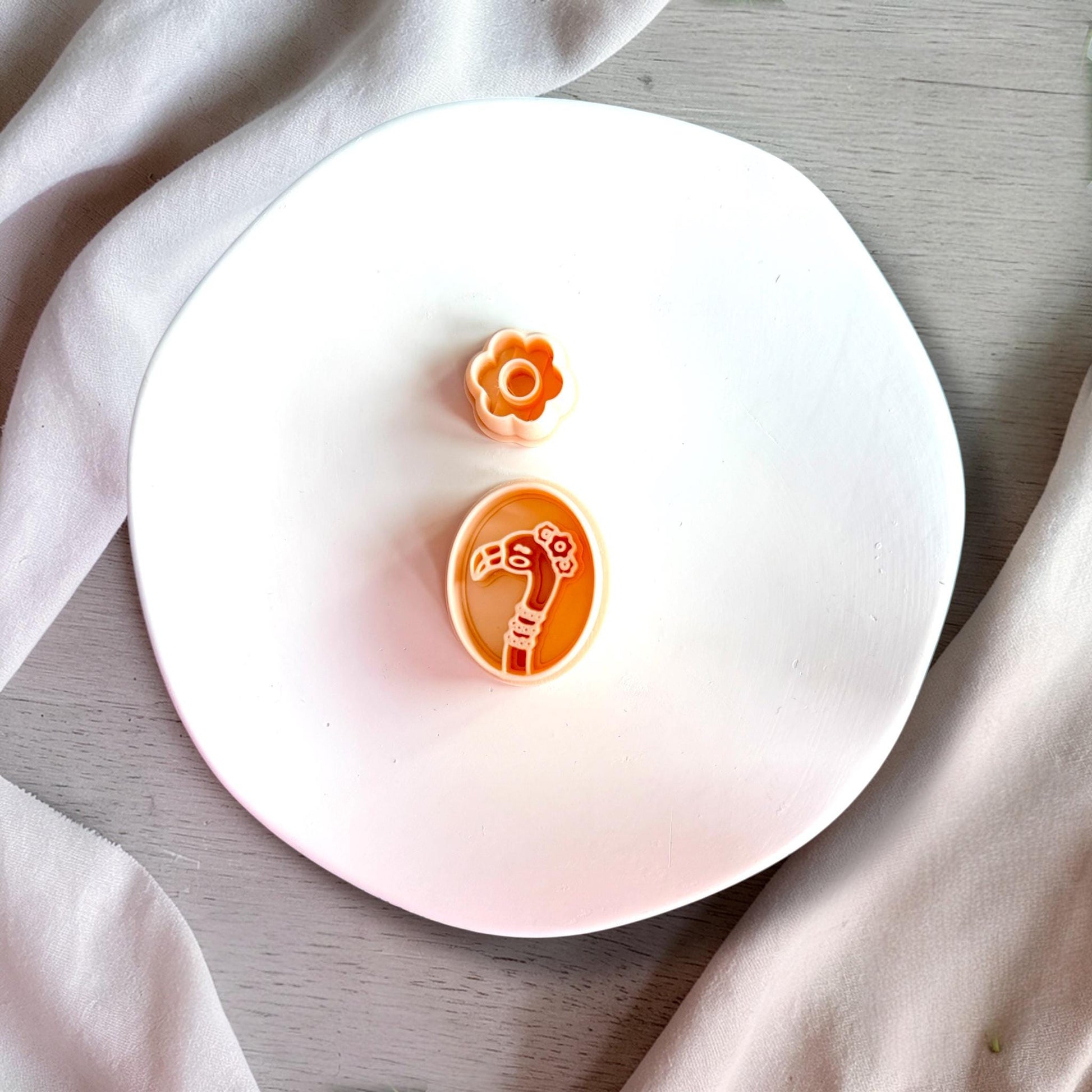 Flamingo and flower polymer clay cutters shown in peach color on white plate with clean detailed edges.