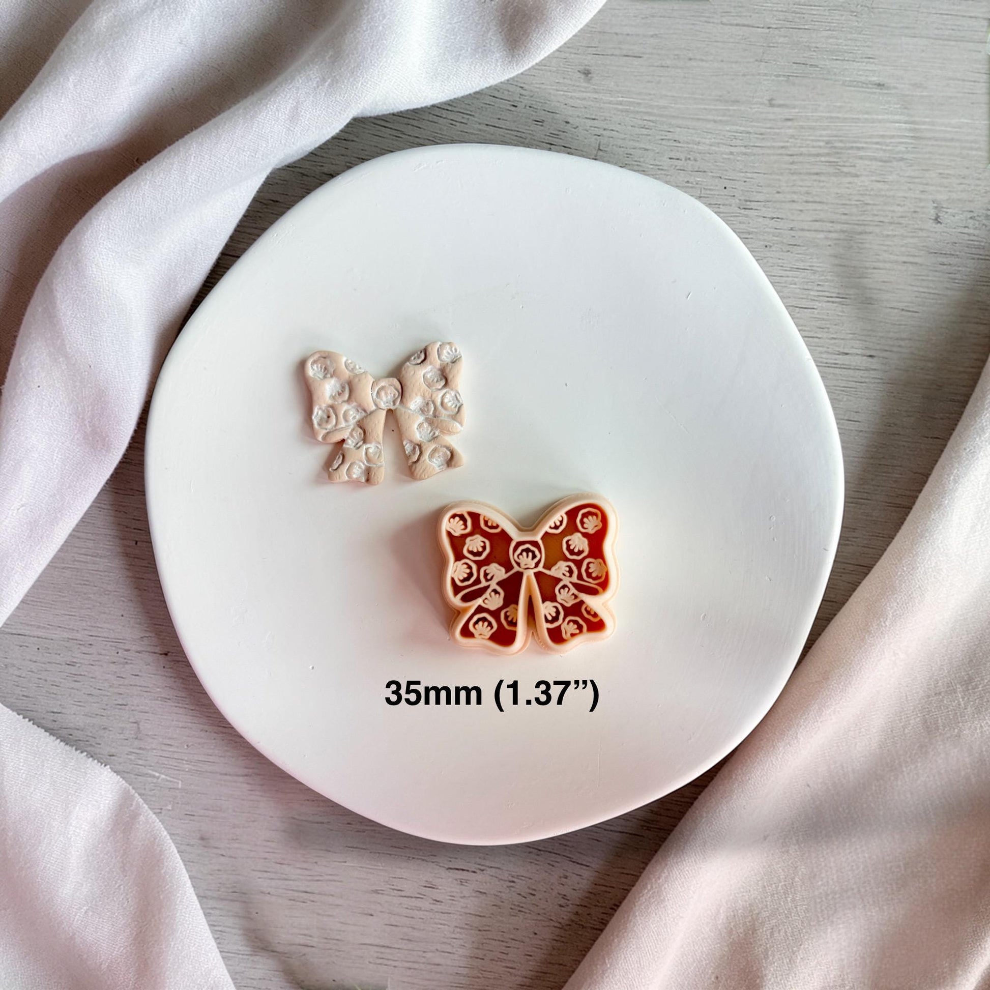 Seashell bow clay cutter and finished polymer clay bow on white plate showing 35mm size detail.