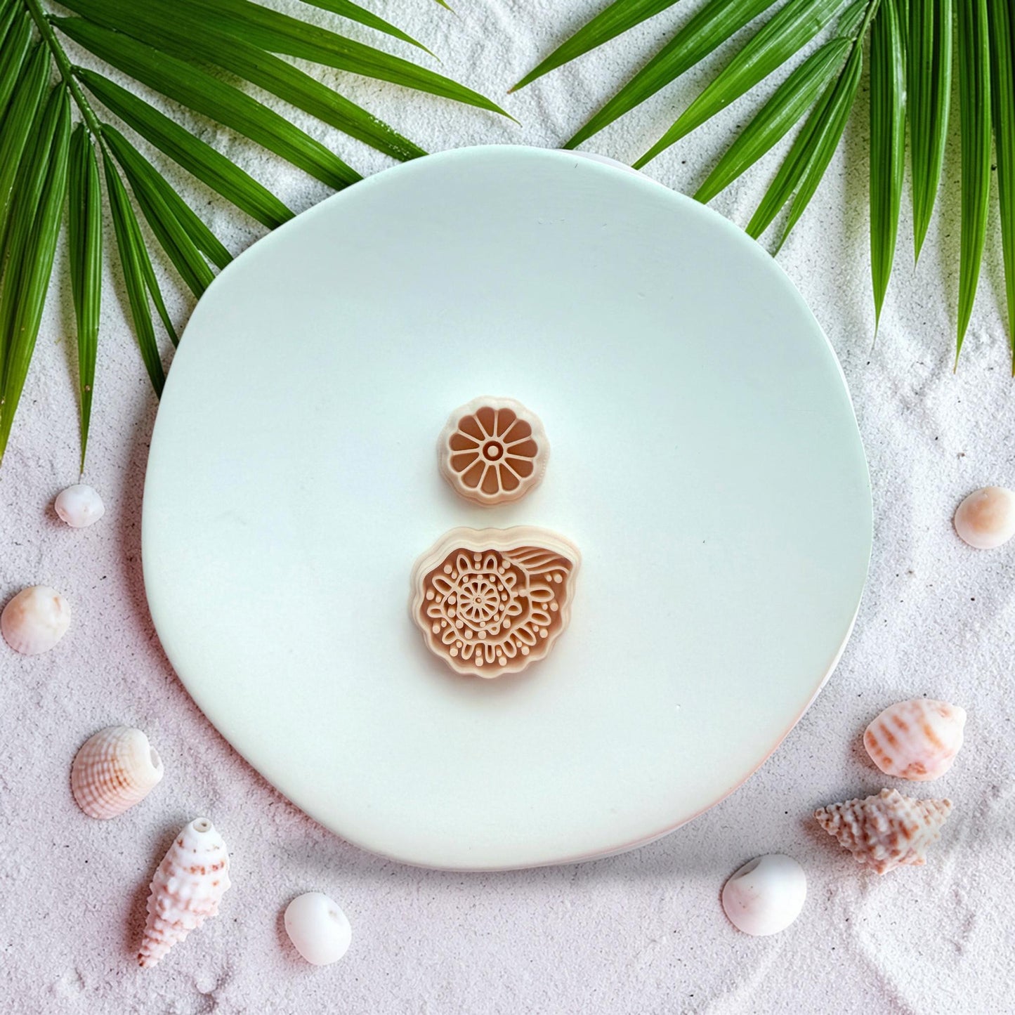 Boho shell polymer clay cutter with floral stud top on beach styled background with sand and shells
