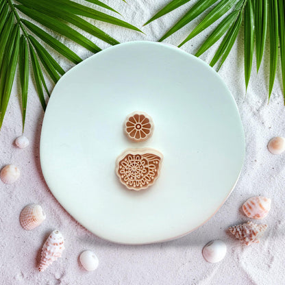 Boho shell polymer clay cutter with floral stud top on beach styled background with sand and shells
