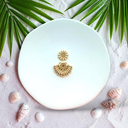 Finished clay earrings showing scallop fan shell design with floral stud top on white background