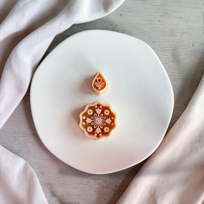 Boho floral mandala polymer clay cutter with teardrop topper on white plate with neutral fabric