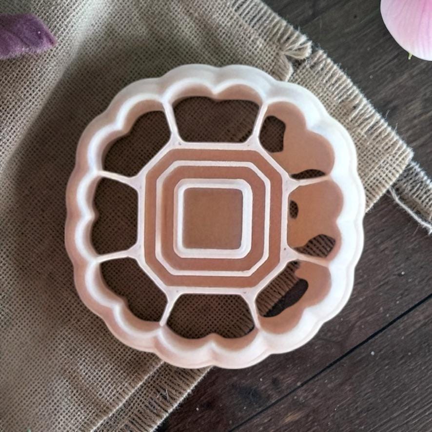 Scalloped heart frame polymer clay cutter with open center on textured fabric