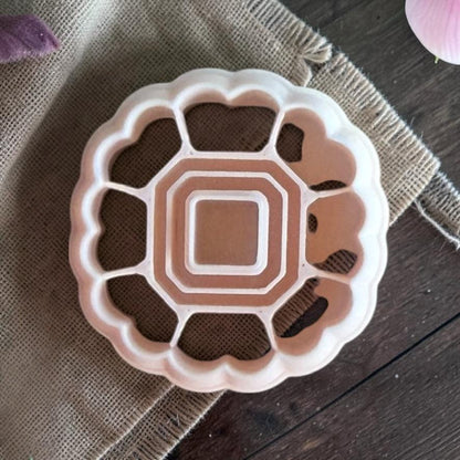 Scalloped heart frame polymer clay cutter with open center on textured fabric