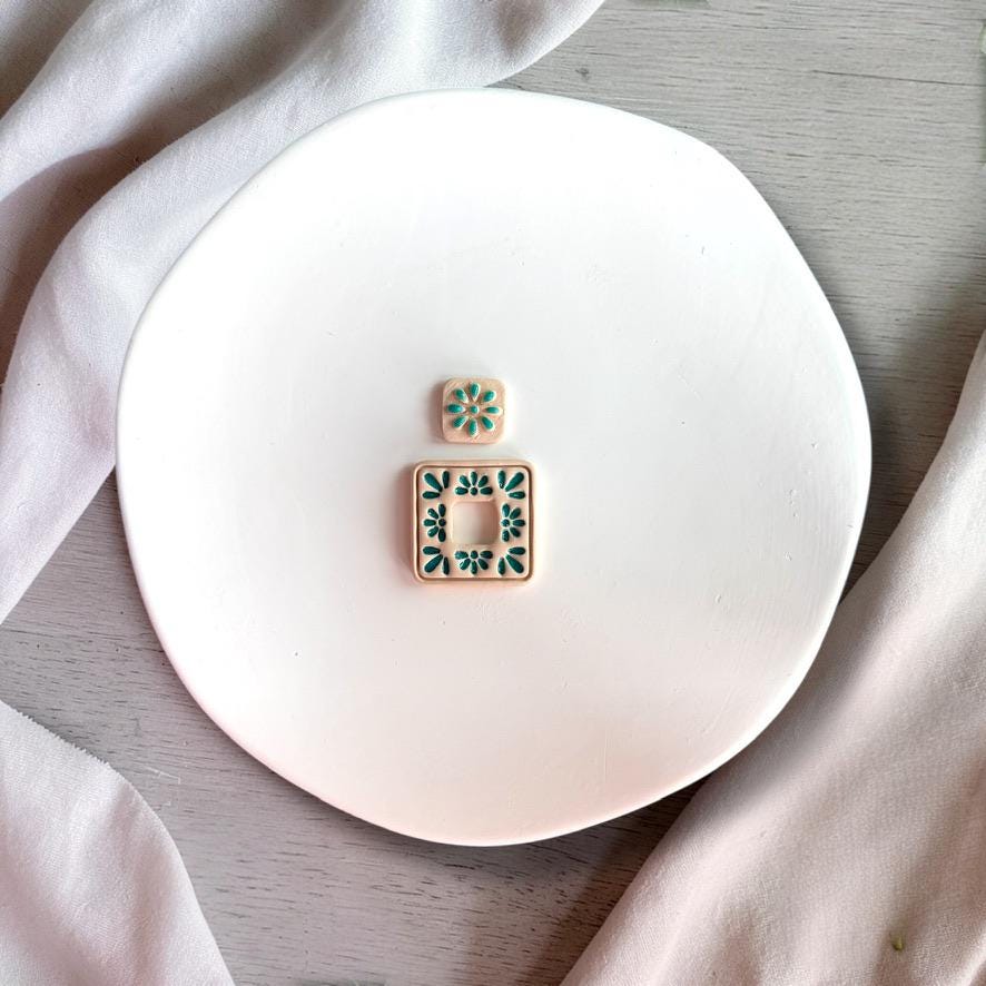 Finished clay earrings showing floral tile design with cut out square center