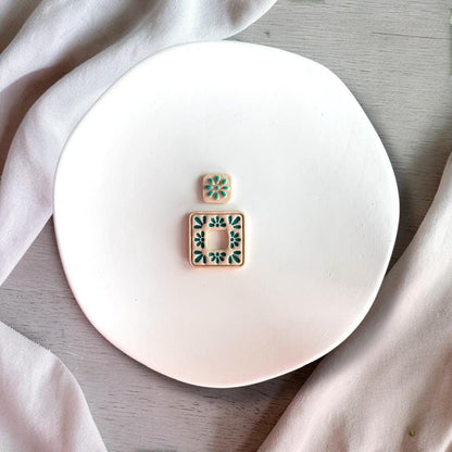 Finished clay earrings showing floral tile design with cut out square center