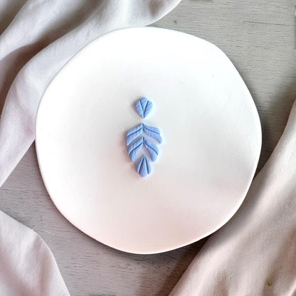 Finished blue clay earring using fern leaf cutter showing texture detail
