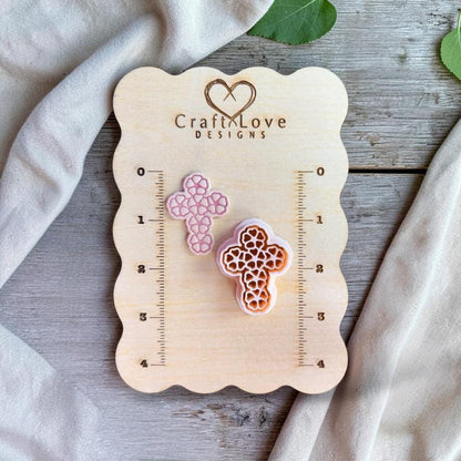 Floral cross polymer clay cutter and sample displayed on wooden size board