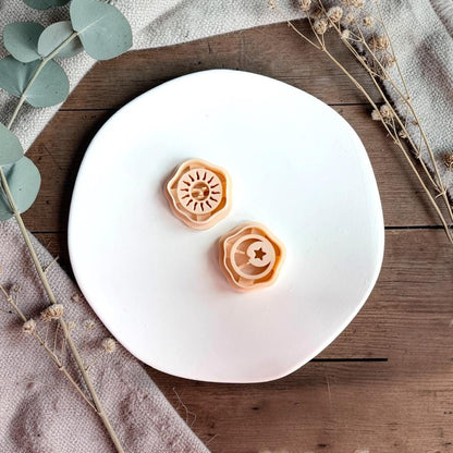 Sun and moon polymer clay cutters displayed on white plate with neutral fabric and greenery