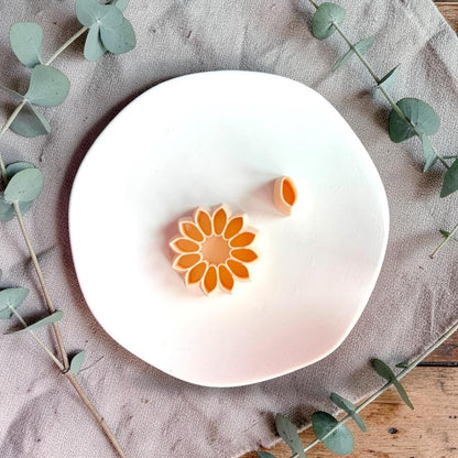 Sunflower cutter and separate petal tool displayed on white plate with greenery