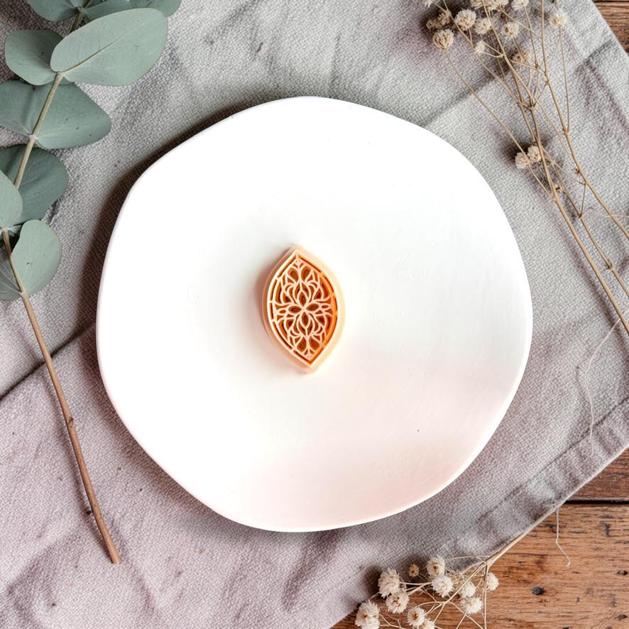 Teardrop stained glass polymer clay cutter on white plate with neutral fabric and greenery
