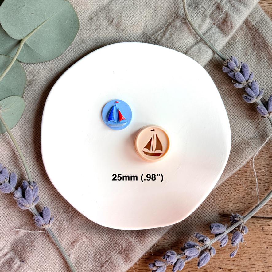 Sailboat cutter with clay piece showing 25mm size reference on white plate