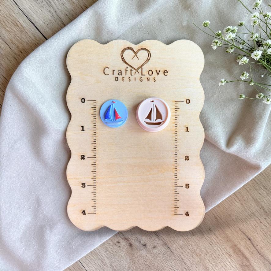 Sailboat cutter and finished clay piece displayed on wooden measurement board