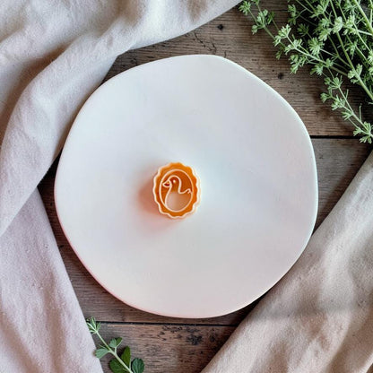 Duck cameo polymer clay cutter on white plate with neutral fabric and greenery