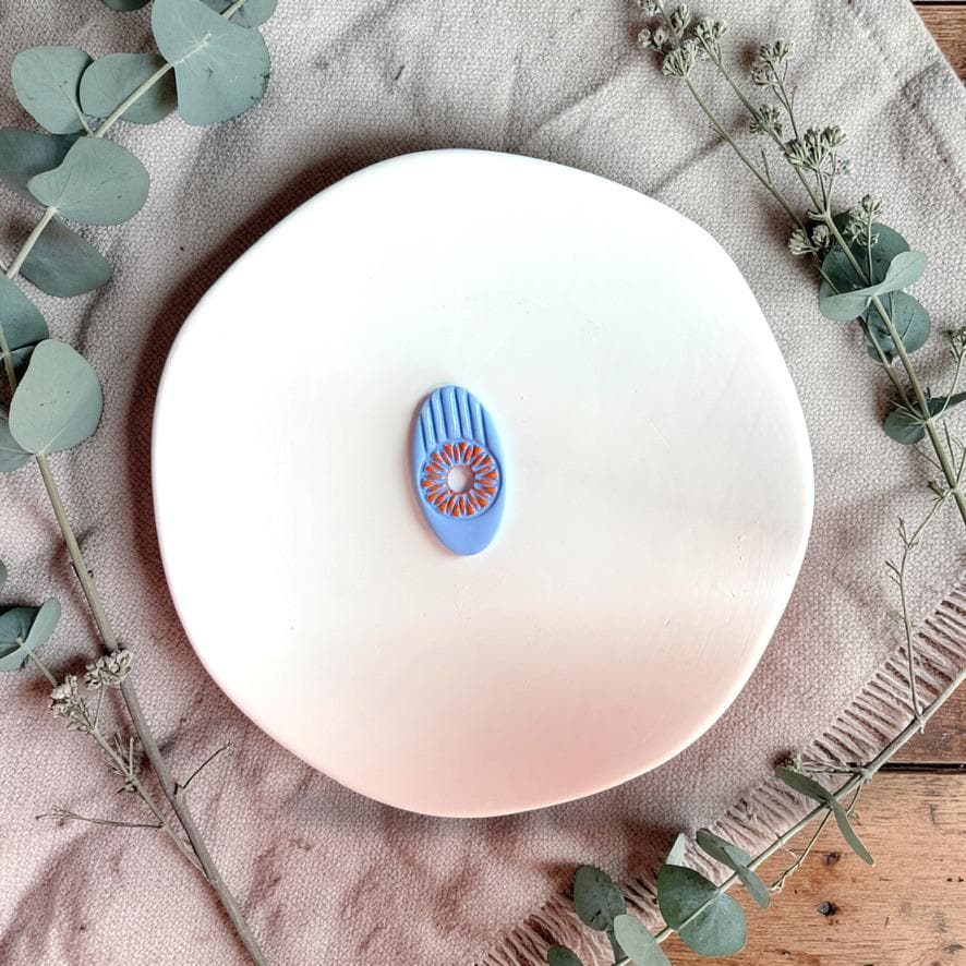Blue clay example showing sunburst floral detail from oval cutter on white plate