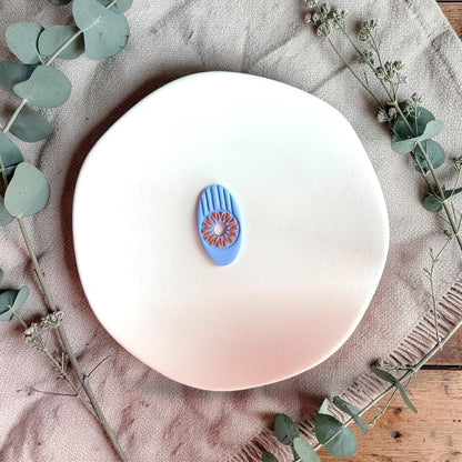Blue clay example showing sunburst floral detail from oval cutter on white plate