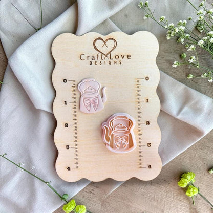 Teapot cutter and clay piece displayed on wooden measurement board