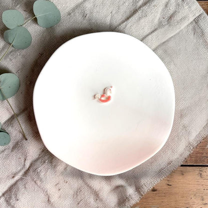 Unicorn floatie polymer clay cutter displayed on white plate with neutral fabric and greenery