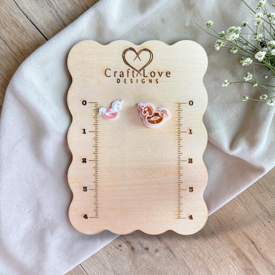 Unicorn floatie cutter and finished clay piece displayed on wooden ruler board