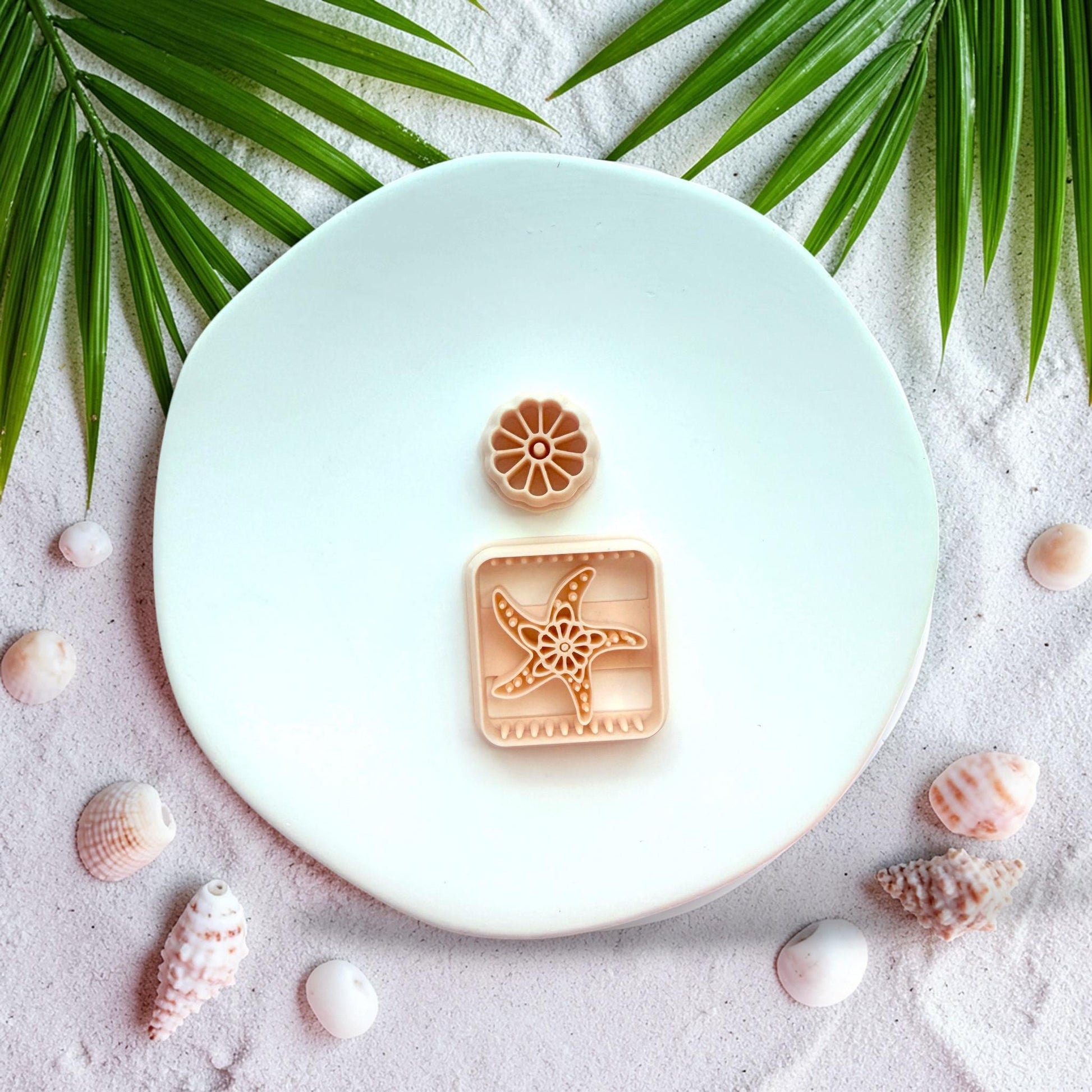 Finished clay earrings showing textured starfish design inside square shape with floral stud top