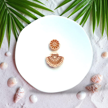 Polymer clay cutter displayed on beach sand with seashells and palm leaves
