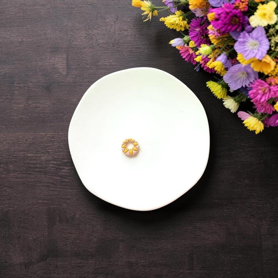 Small daisy clay piece with open center on white background
