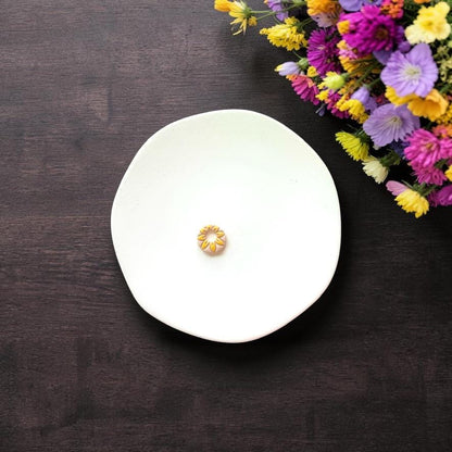 Small daisy clay piece with open center on white background