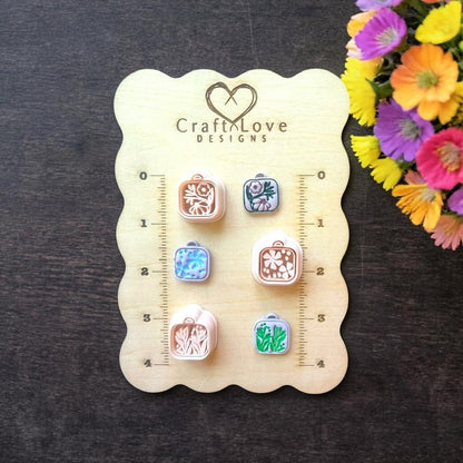 Square floral locket polymer clay cutters with loop on sizing board showing multiple designs