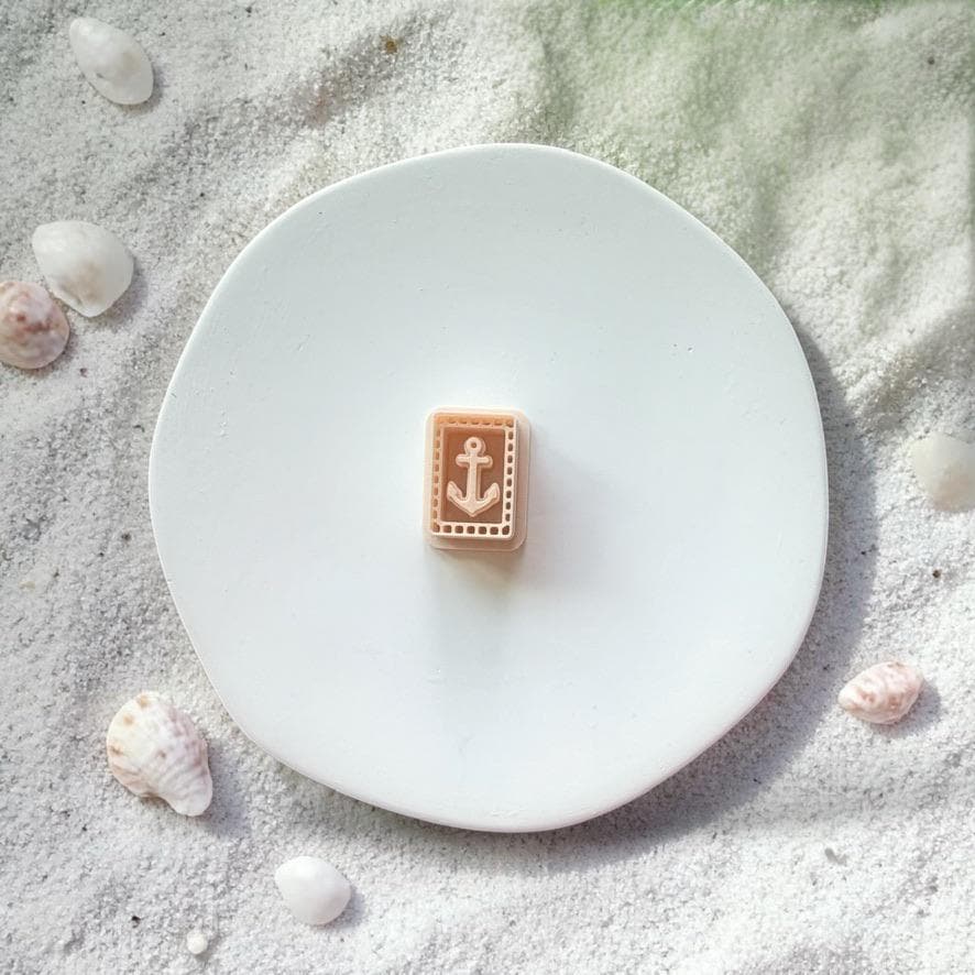 Anchor tile polymer clay cutter shown on white plate with beach sand and shells background