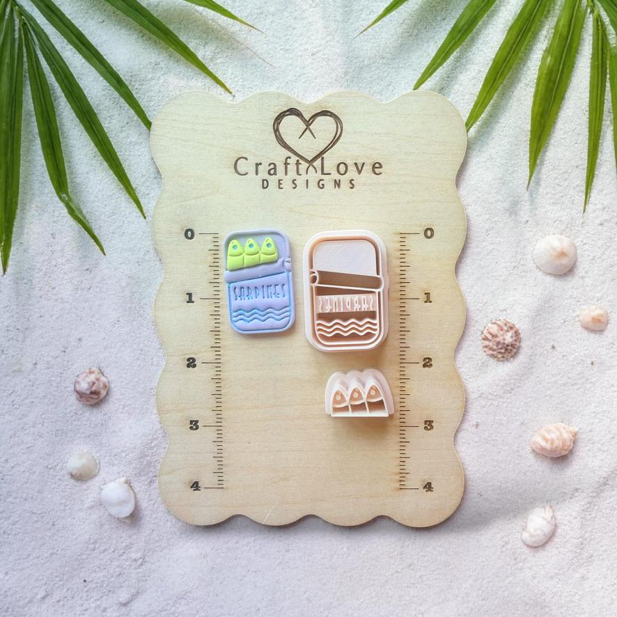 Sardine tin cutter and clay pieces displayed on wooden sizing board with coastal decor