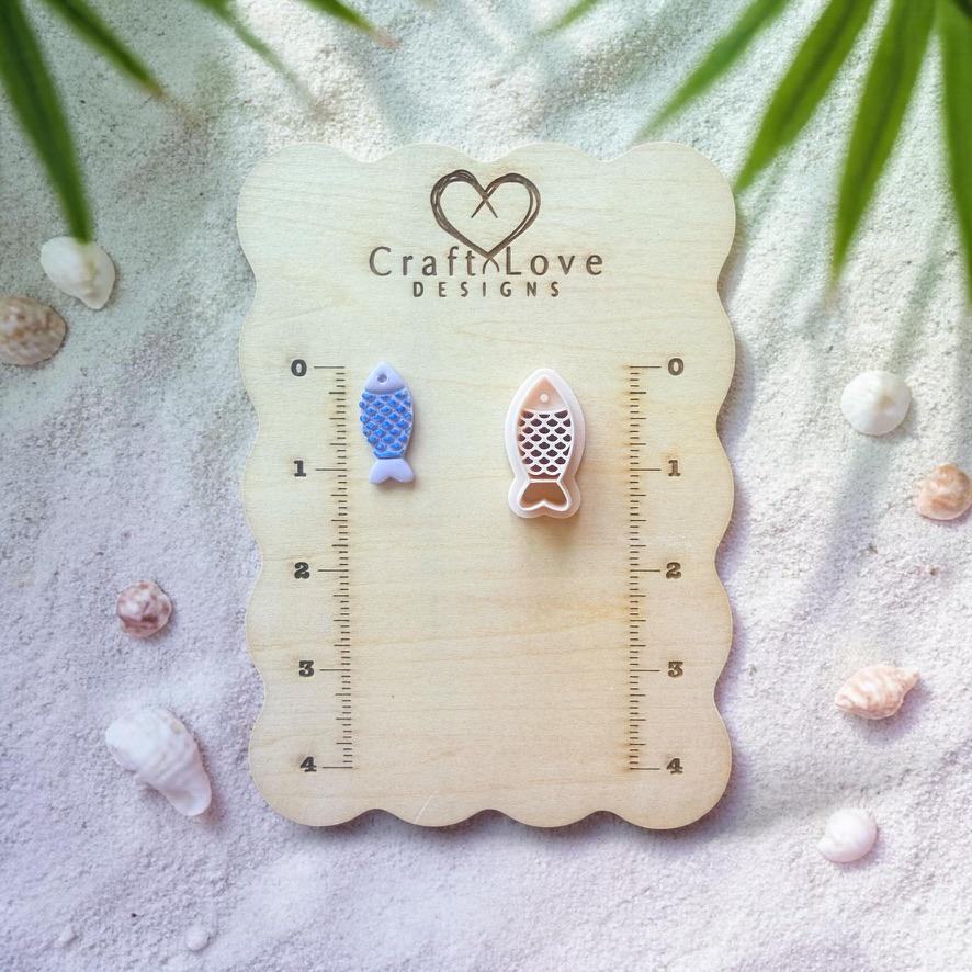 Fish clay cutter and finished pieces displayed on wooden sizing board with coastal decor