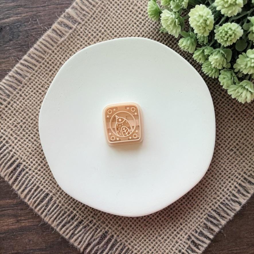 beige bird tile polymer clay cutter on white plate with greenery