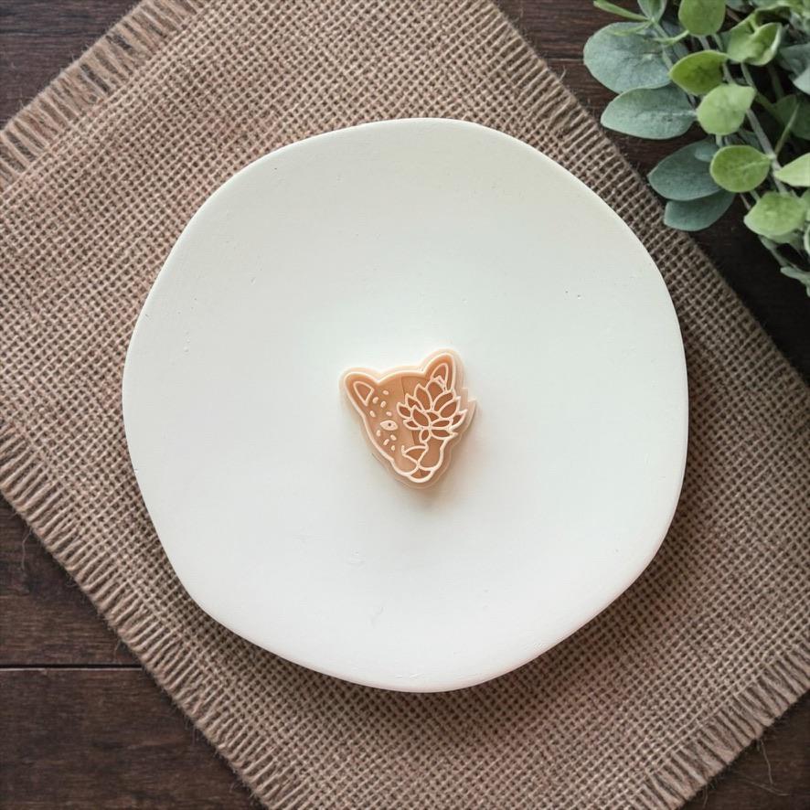 beige floral leopard face clay cutter on white plate with rustic fabric background
