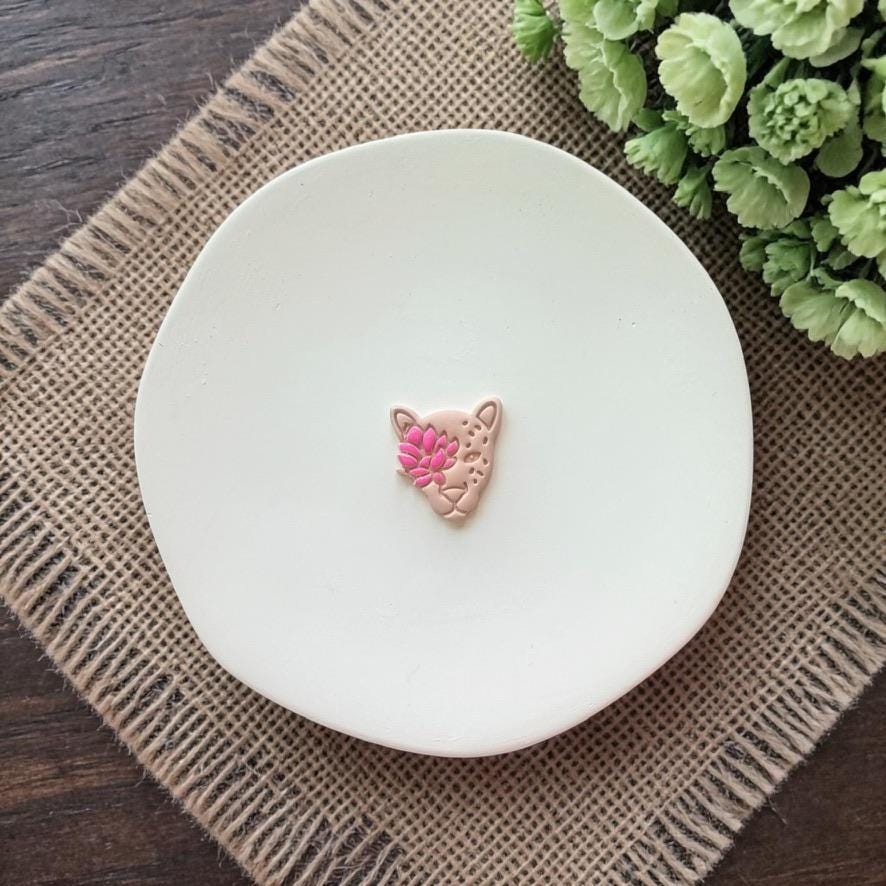 finished clay leopard face earring with pink flower detail on white plate