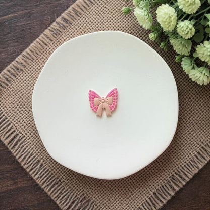 small pink butterfly bow clay earring on white plate
