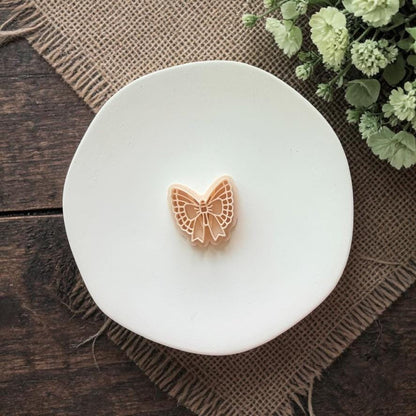 butterfly shaped clay cutter with lace wings and bow on white plate