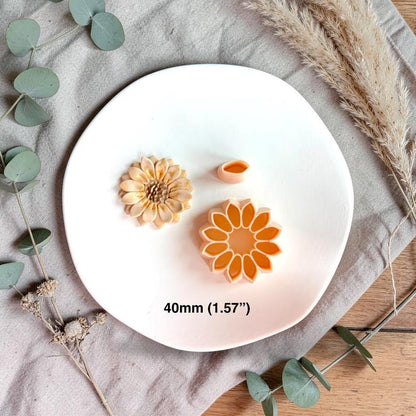 Sunflower clay piece with cutter and petal tool showing 40mm size reference on white plate