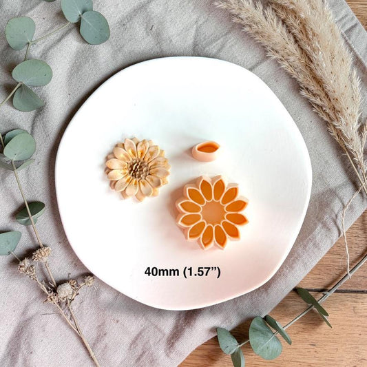 Sunflower clay piece with cutter and petal tool showing 40mm size reference on white plate