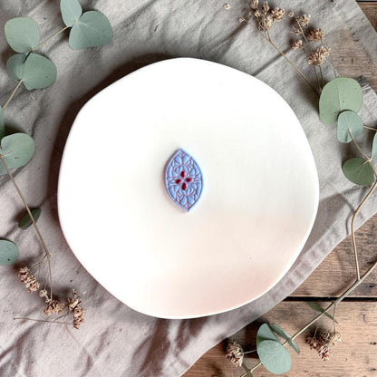 Blue teardrop clay piece with stained glass floral pattern on white plate