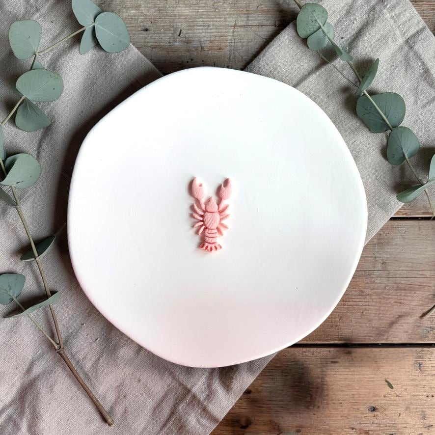 Pink lobster clay piece on white plate showing embossed detail