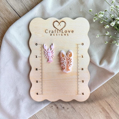Lobster cutter and finished clay piece displayed on wooden measurement board