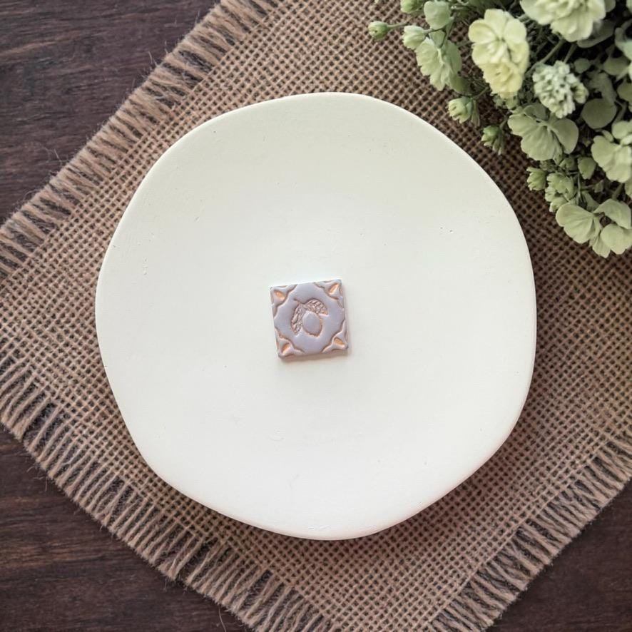 lemon tile clay earring on white plate with burlap background