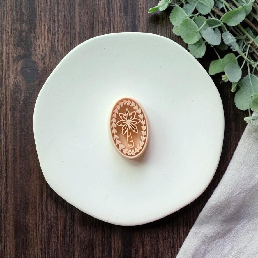 oval palm tree polymer clay cutter on white plate with greenery and wood background