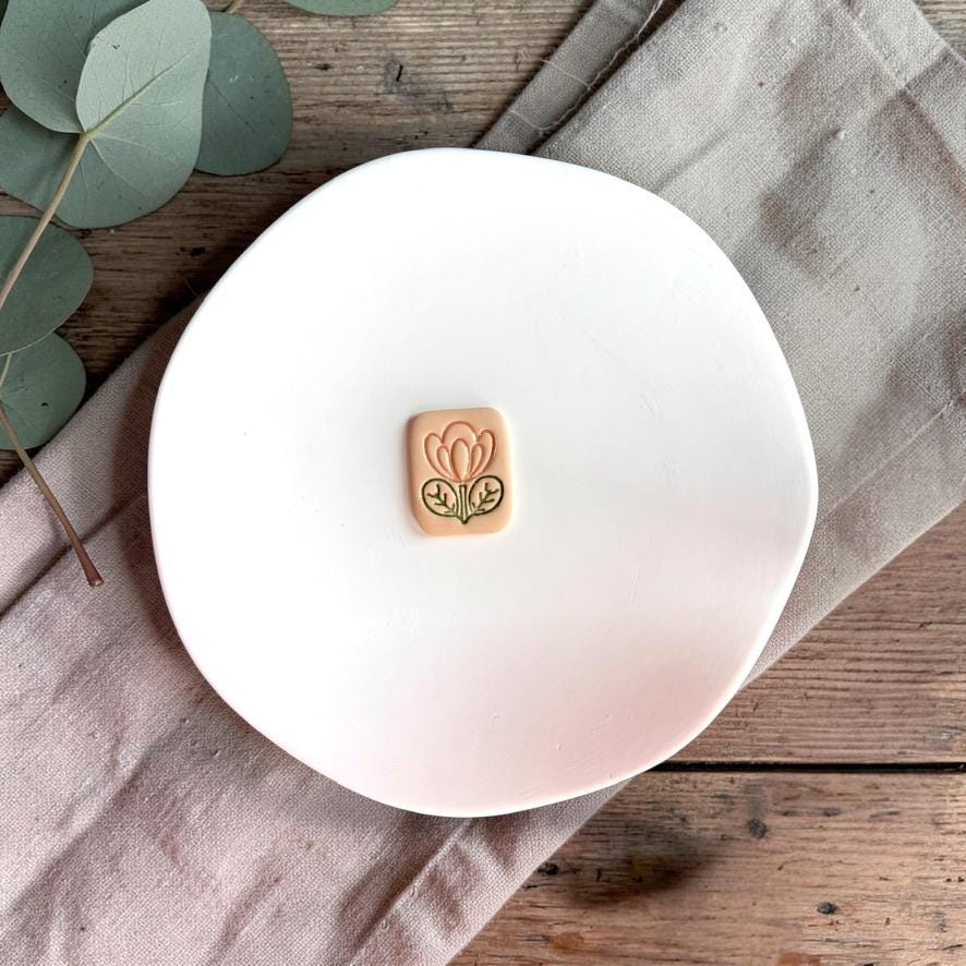 Clay floral tile piece showing detailed flower design on white plate