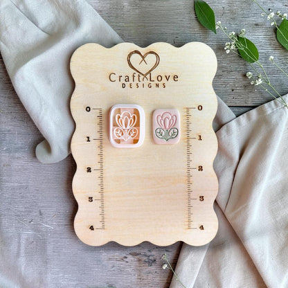 Floral tile cutter and finished clay piece displayed on wooden measurement board