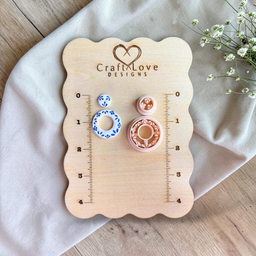 Cutter and finished earrings displayed on wooden measurement board