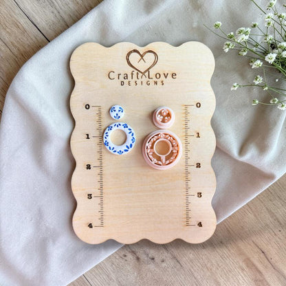 Cutter and finished earrings displayed on wooden measurement board