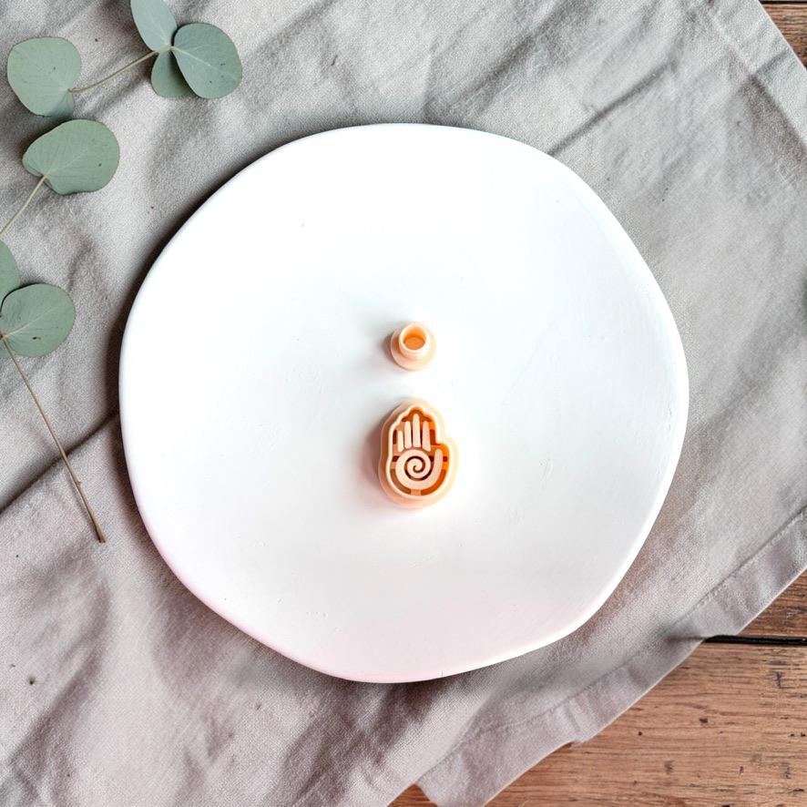 Hamsa hand polymer clay cutter with spiral detail on white background